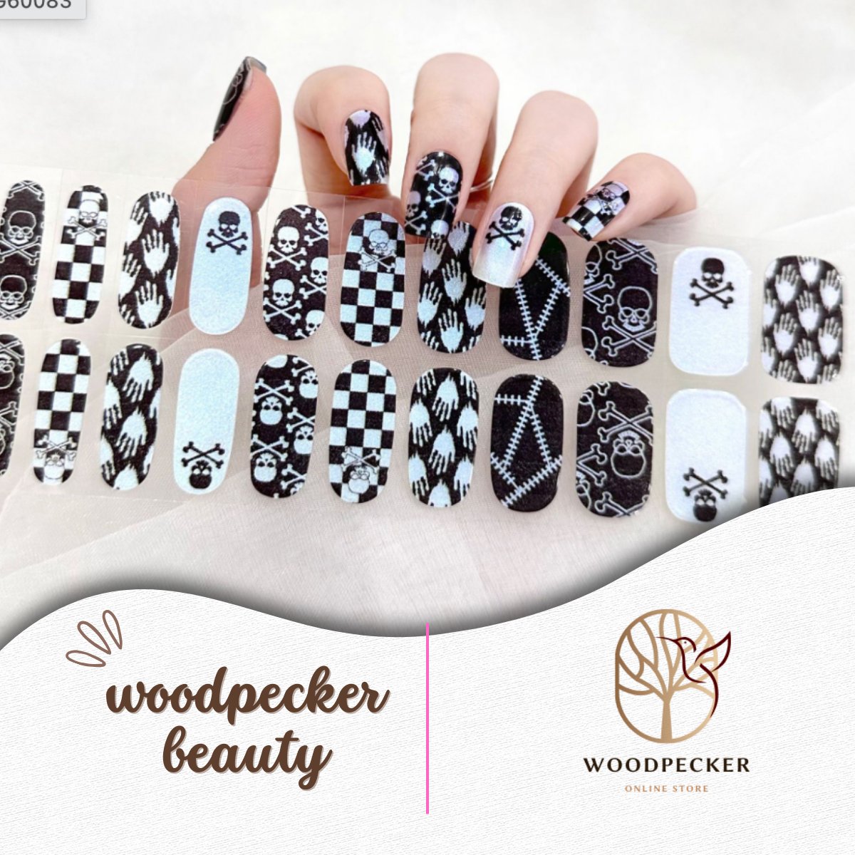 Hand with punk-inspired semi-cured gel nail wraps featuring skulls, bones, checkerboard, and gothic stitching, UV lamp required