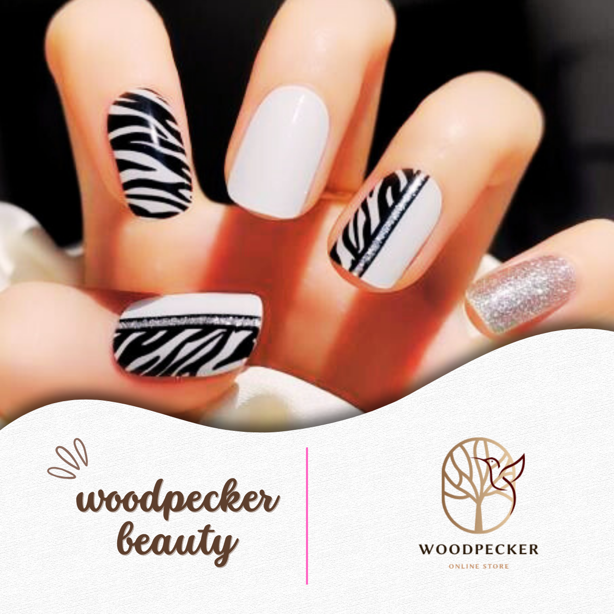Hand with black and white zebra pattern nail wraps, silver glitter accent, and solid white nails