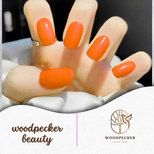 Close-up of glossy orange gel nail stickers applied on natural nails – Woodpecker Beauty