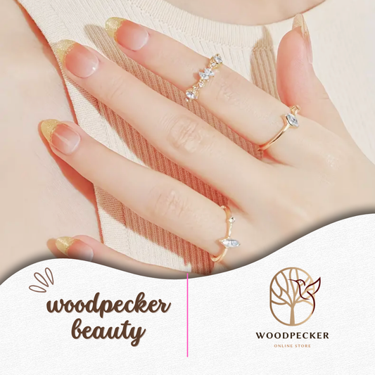Close-up of nude gel nail stickers with fine gold tips and rings – Woodpecker Beauty