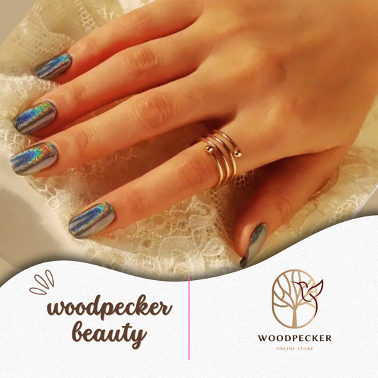 Hand with peacock-inspired aurora nail stickers featuring blue, green, and gold shimmer – Woodpecker Beauty