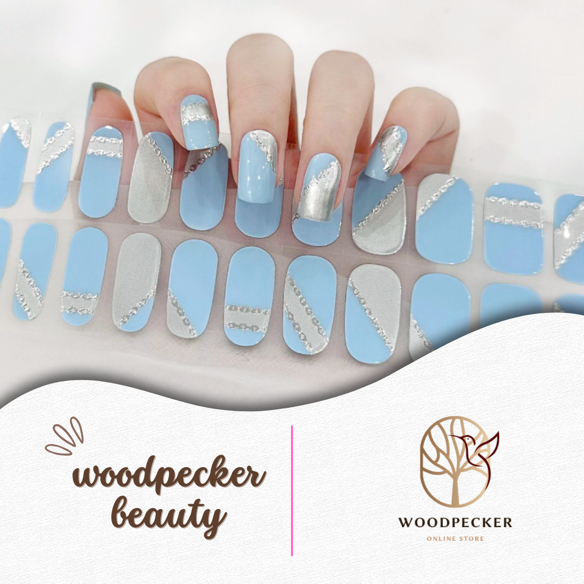 A hand showing light blue and silver nail stickers with diagonal glitter striping from Woodpecker Beauty
