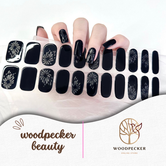 Hand with glossy black semi-cured gel nail wraps featuring subtle firework patterns, UV lamp required