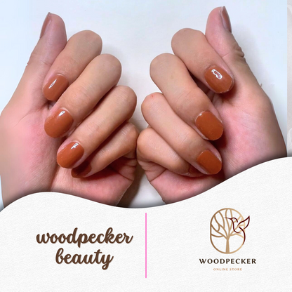 Both hands showing warm caramel gel nail stickers in a cozy natural light setting.

