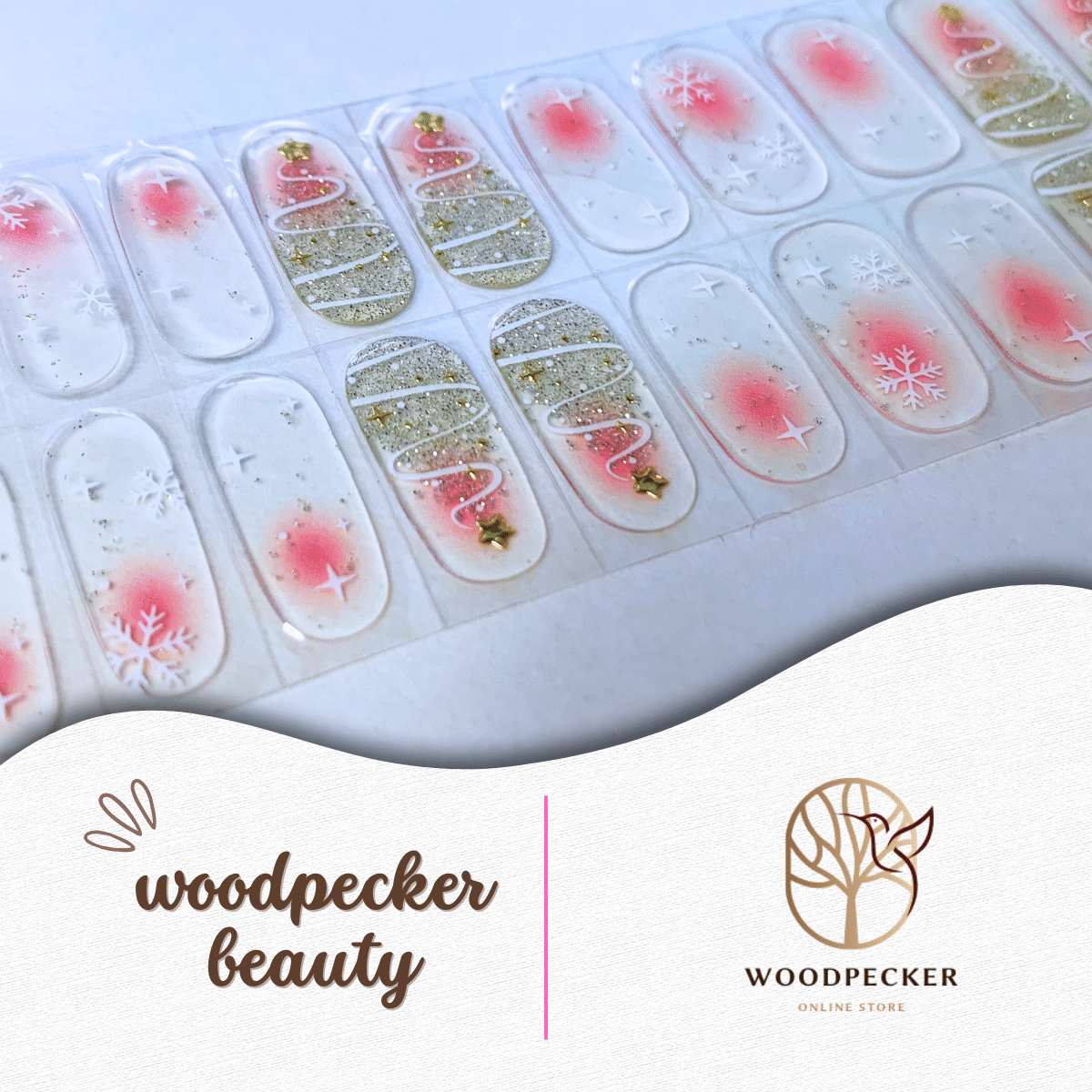Flat lay of festive nail wraps with snowflakes, gold Christmas tree swirls, and translucent pink backgrounds.

