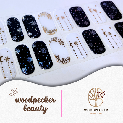 Flat lay of winter-themed nail stickers with navy and nude colors, decorated with snowflakes and gold foil stars.
