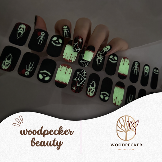 Hand with horror-themed glow-in-the-dark semi-cured gel nail wraps featuring skulls, webs, blood, and spooky faces, UV lamp required
