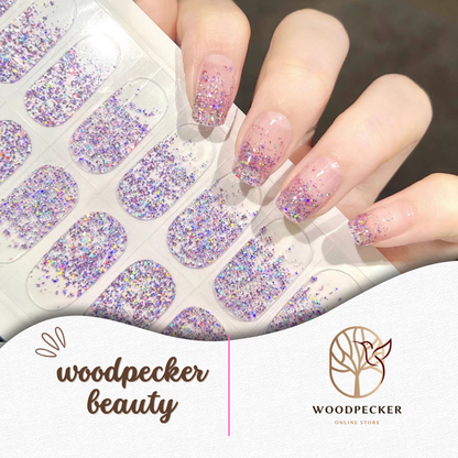 Hand holding a sheet of pink and purple glitter nail wraps, ready to apply
