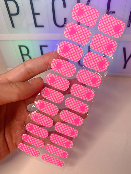 Hand holding a set of pink grid heart nail wraps