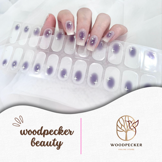 Hand with purple semi-cured gel nail wraps featuring glow-like centers and starburst accents, UV lamp required