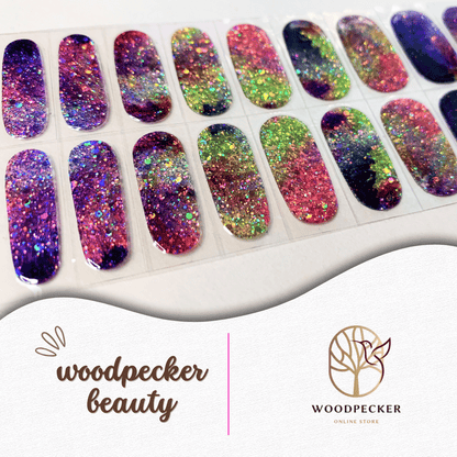 Flat lay of rainbow galaxy nail wraps with chunky glitter and multicolor swirls.
