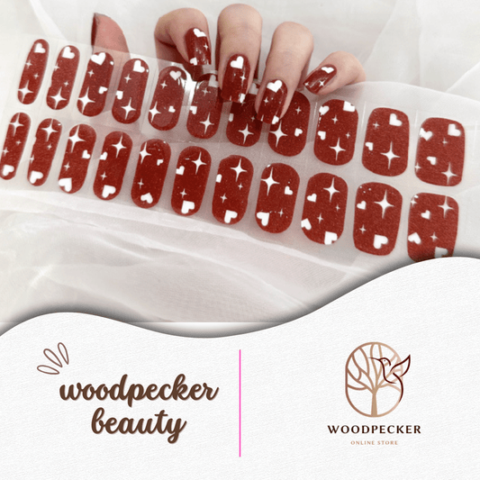 Hand with glossy brick red nail stickers featuring playful white star patterns.
