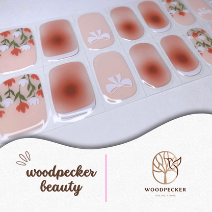 Person holding floral rose nail wraps under soft indoor lighting.
