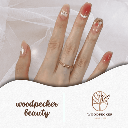 Hand with rosy gradient nail stickers featuring floral and leaf details.
