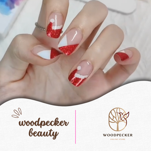 Hand wearing nail stickers with red glitter Santa hat design and white trim on a nude base.
