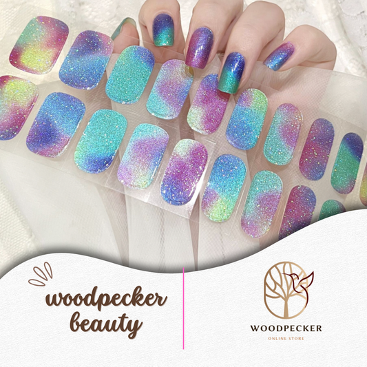 Hand with holographic gradient rainbow glitter semi-cured gel nail wraps in purple, blue, and green tones, UV lamp required
