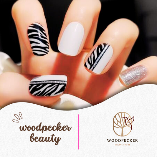 Hand with black and white zebra pattern nail wraps, silver glitter accent, and solid white nails